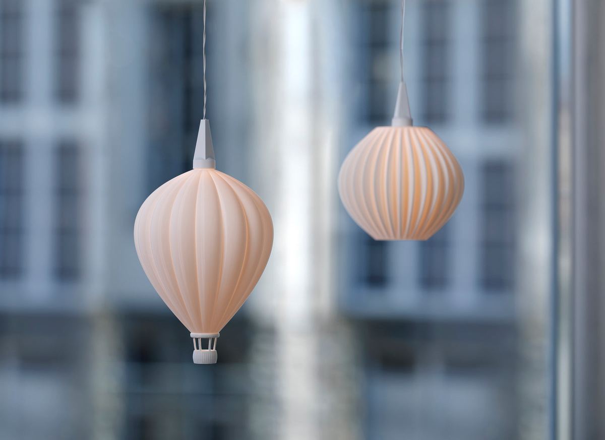 Zwei beleuchtete Hängelichter von InnoCreo, ein Heißluftballon und ein gerippter Schirm, hängen vor einem Fenster