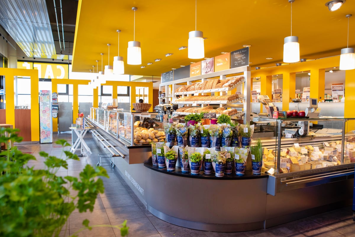 Blick durch den Verkaufsraum: Bistro links, Backshop mit Broten in der Mitte, Frische- und Käsetheke rechts